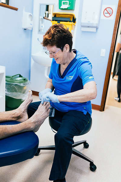 A woman receives a foot examination from a doctor in a clinical setting.