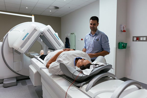 A man lies inside an MRI machine in a hospital, undergoing a medical imaging procedure.