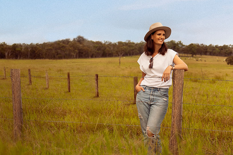 A woman leaning on a pole in a farm.