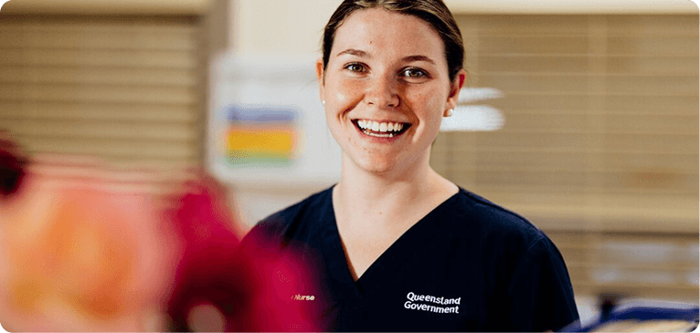 A smiling woman in a hospital uniform poses for the camera, conveying warmth and professionalism.