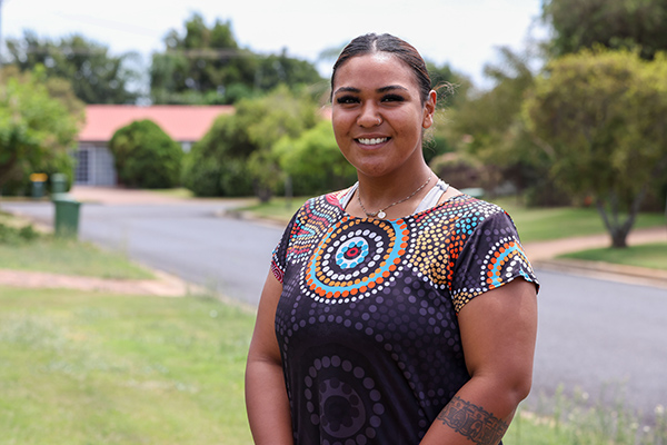 A woman stands on a footpath in a residential street.