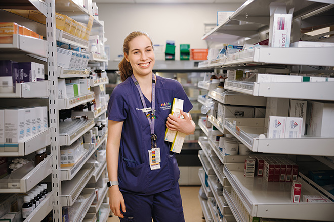 A woman browsing shelves in a pharmacy store, examining products with a thoughtful expression.
