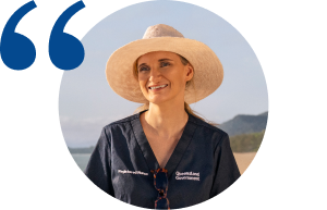 Profile photo of Hayley walking on sunny beach in hat