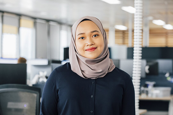 A woman in a hijab standing in a in a modern office environment.