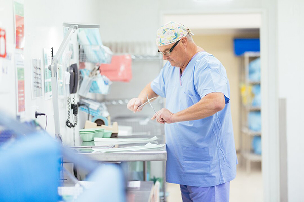 A nurse in scrubs prepares instruments in a hospital operating room for an upcoming surgery.