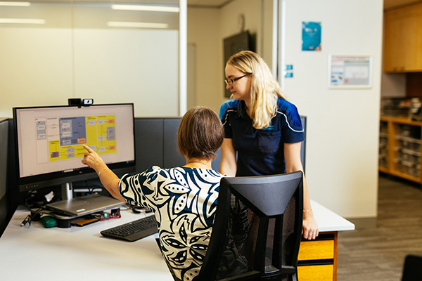 Two women collaborating on a computer in a modern office setting.
