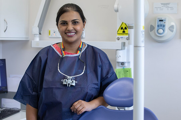 A dentist stands behind a chair in a dental surgery.