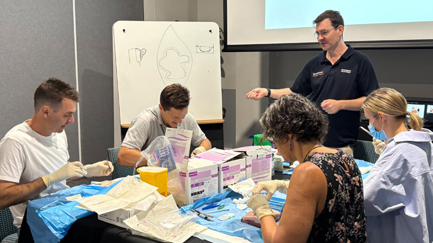 A group of medical professionals seated at a table, discussing surgical equipment and procedures.